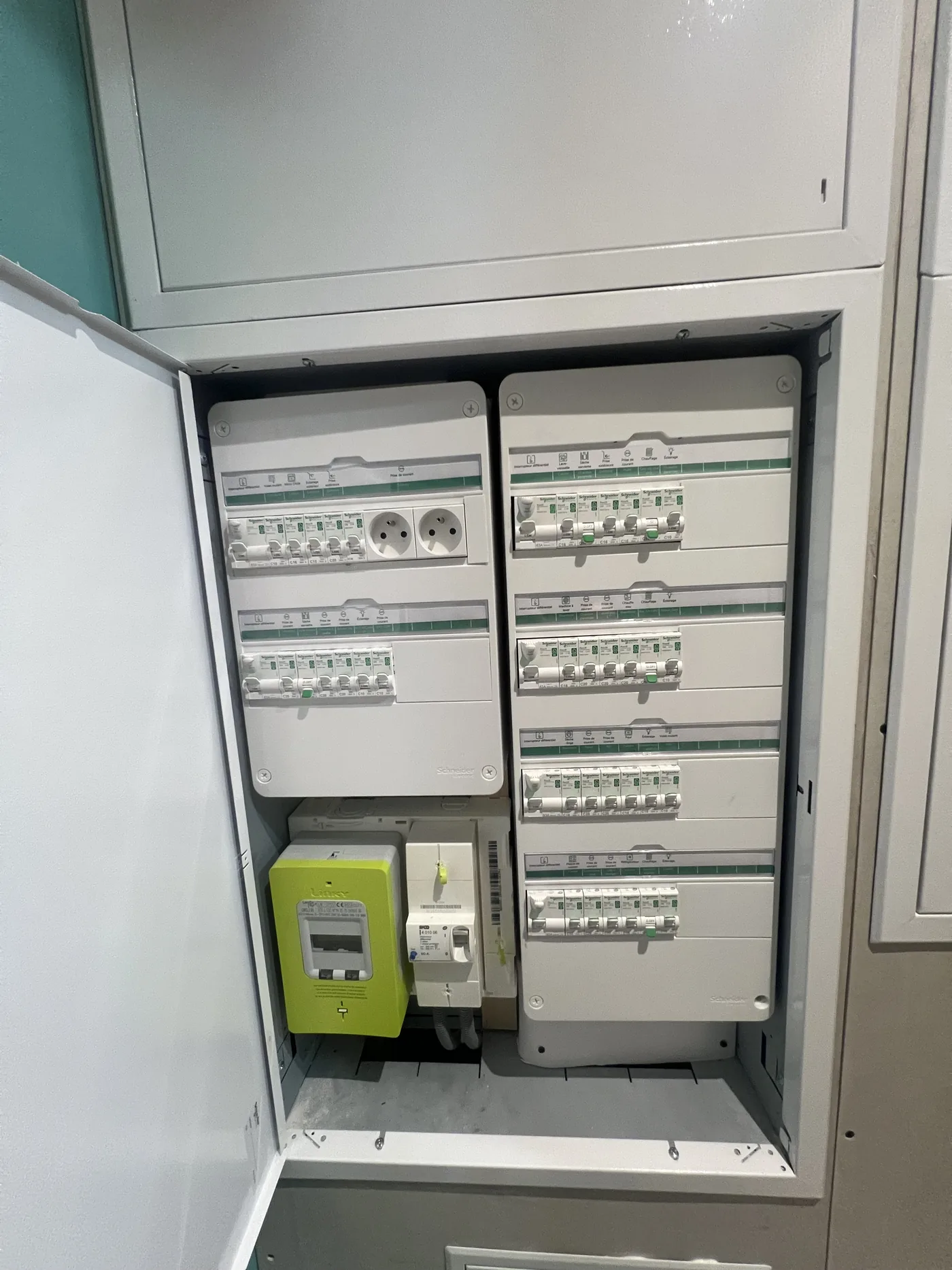 Tableau électrique neuf à Nantes : deux coffrets Schneider, un interrupteur différentiel par rangée, départs repérés par pictogrammes, disjoncteur de branchement et compteur Linky en partie basse